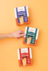 Three Absolutely Gluten Free Grain Free Flatbreads boxes on an orange background.